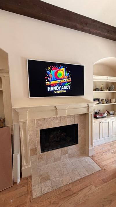 TV mounted above a travertine tile fireplace