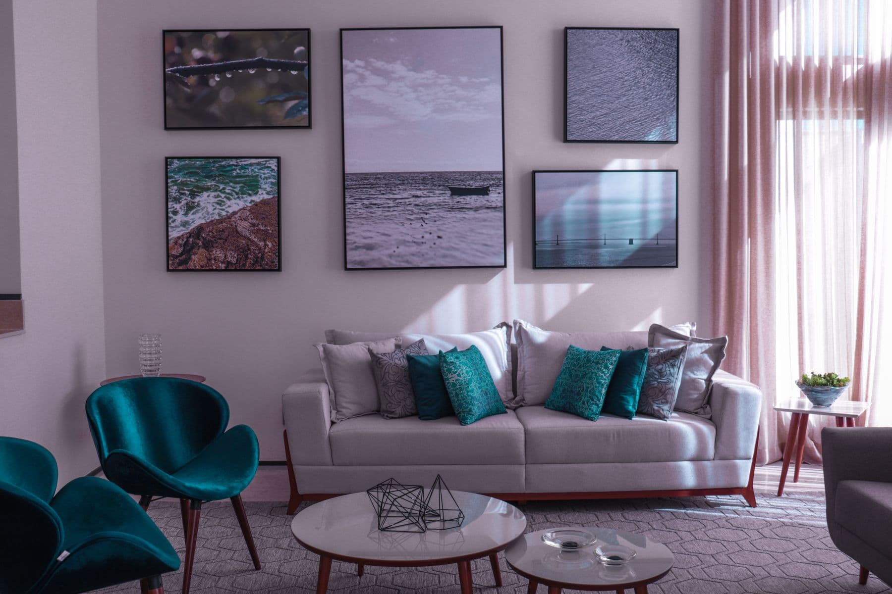 A gallery wall of five framed prints hung level above a sofa in a bright living room