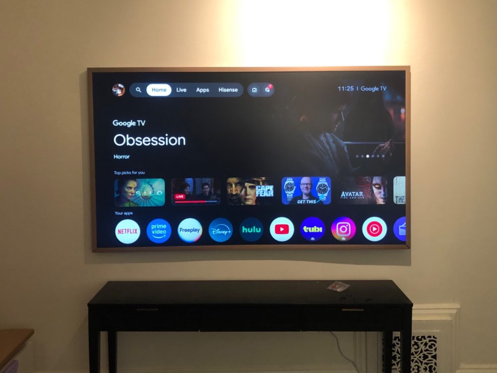 TV mounted above a black console table, lit by a warm wall light